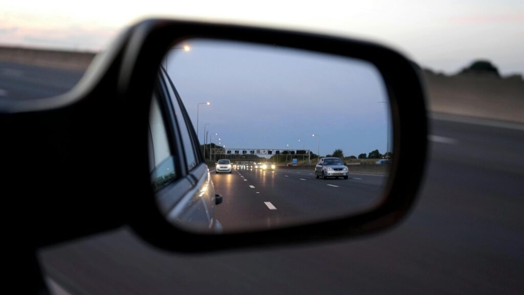 pexels-photo-133826-133826 View of cars on the highway reflected in a vehicle's side mirror at twilight, capturing motion and speed.